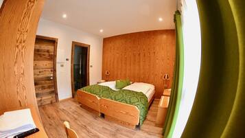 Un dormitorio con una cama de madera, un escritorio con silla y una cortina verde.