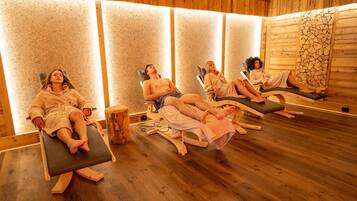 Eine Sauna mit Holzwänden und -böden, mehreren Liegestühlen und einer zentralen Holzkonstruktion.
