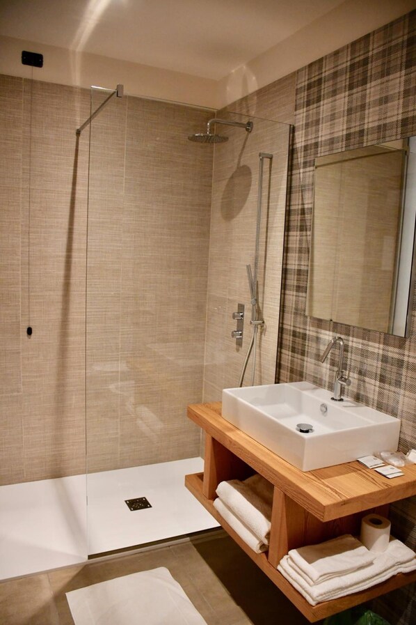 A modern bathroom with a glass-enclosed shower, a wooden vanity with a sink, and a large mirror.