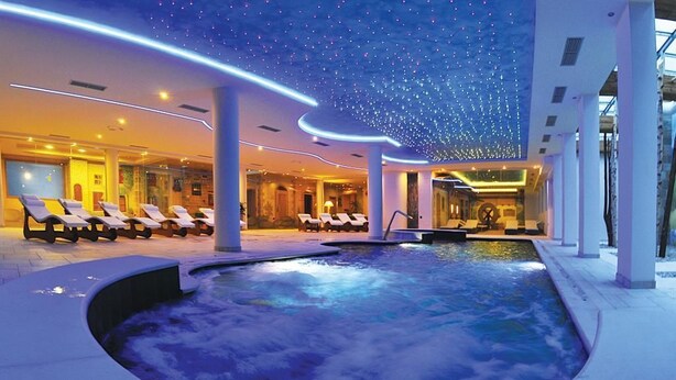 A spa area with a hot tub, lounge chairs, and a ceiling with star-like lights. - Hotel Alpenrose (Altopiano della Vigolana)