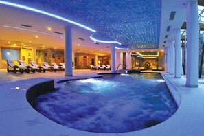 A spa area with a hot tub, lounge chairs, and a ceiling with star-like lights.