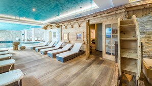 A spa area with wooden flooring, sun loungers, a wooden staircase, and a stone wall. - Hotel Alpenrose (Altopiano della Vigolana)