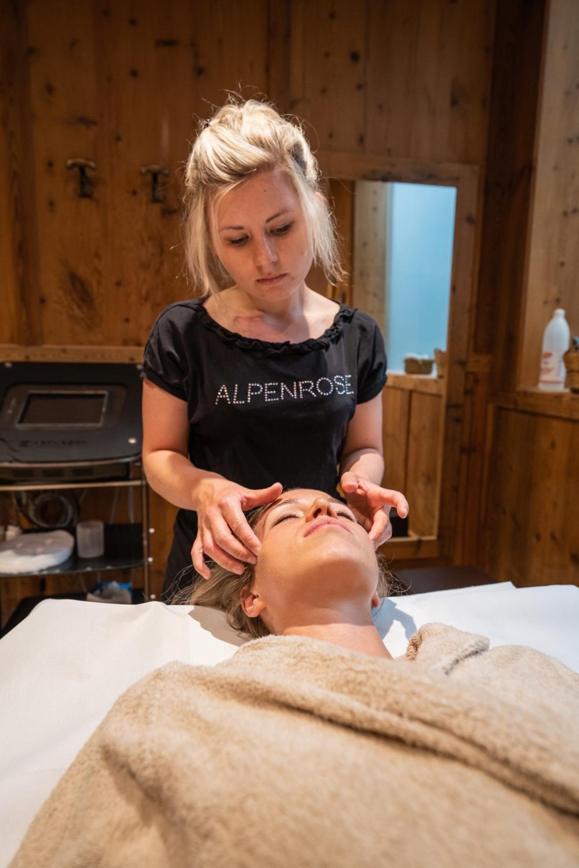 A person receiving a massage in a room with wooden walls and a massage table.