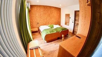 A modern bedroom with a curved wooden headboard, a wooden desk, and a green bedspread.