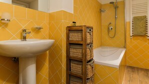 A bathroom with a white sink, a bathtub, and a shower. There are wicker baskets and a towel rack on the wall. - Spanish Steps Studio Apartment (Rome)