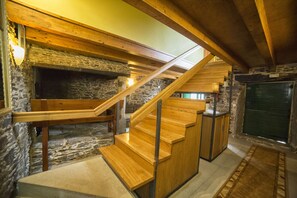 A wooden staircase with a stone wall and a fireplace. - O Acivro Aloxamentos Rurais (O Pino)