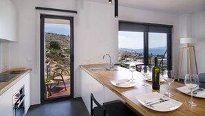 Une cuisine moderne dotée d’un plan de travail en bois, d’un évier encastré et offrant une vue sur le paysage grâce à de grandes fenêtres.