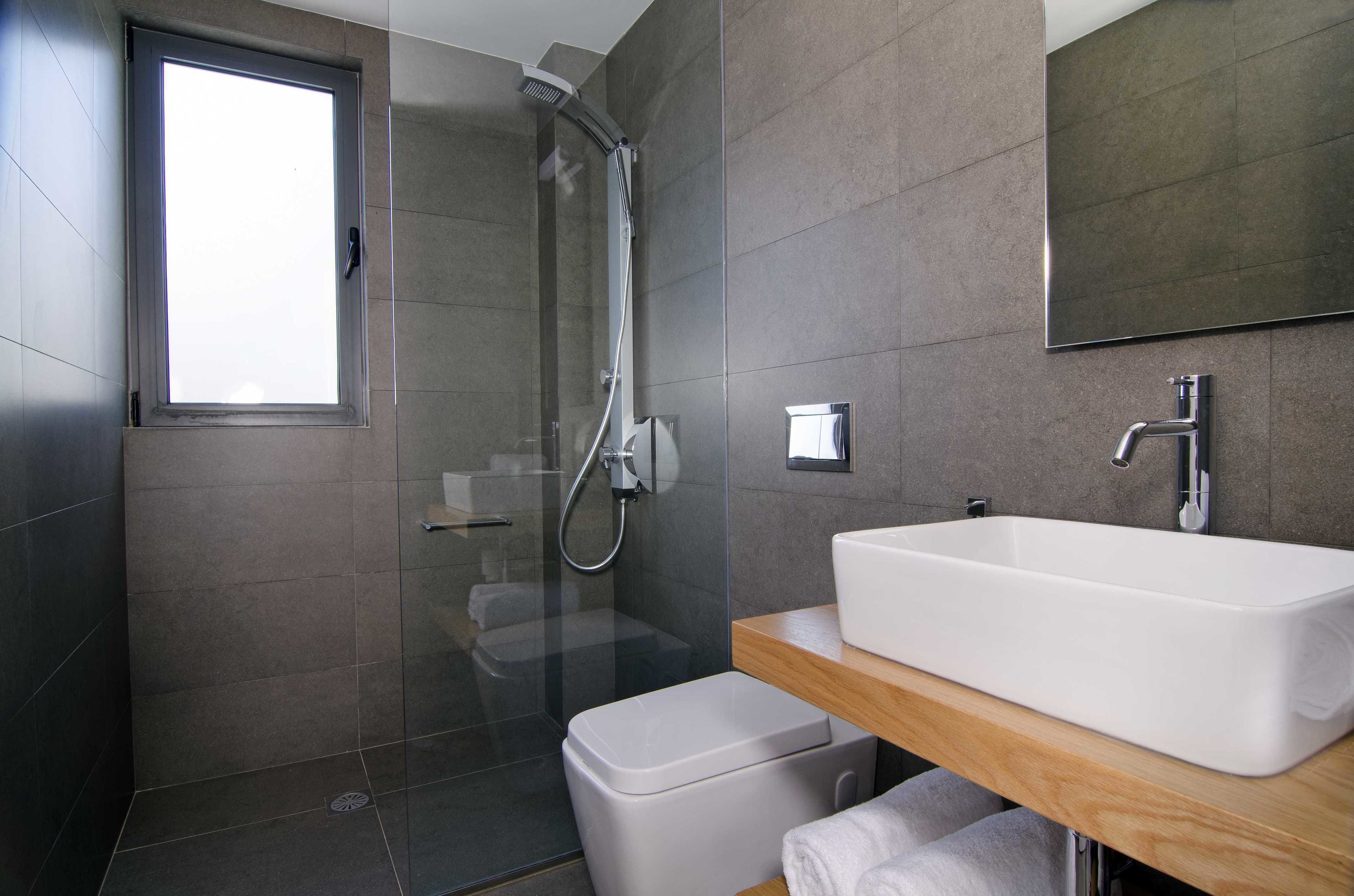 A modern bathroom with a glass-enclosed shower, a white sink, and a wooden vanity.