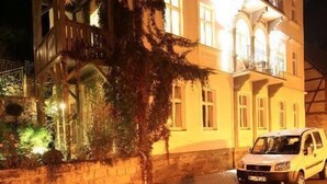 Un edificio de varios pisos con balcones y un coche estacionado adelante.