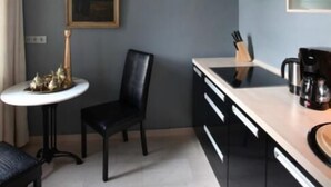 Una cocina compacta con una encimera, una cafetera y una pequeña mesa con una silla.