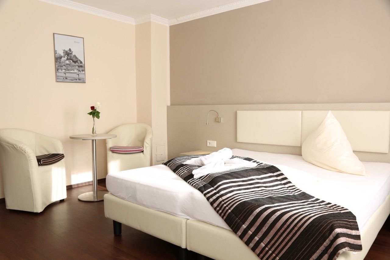 A hotel room with a bed, a chair, a small round table, and a picture on the wall.