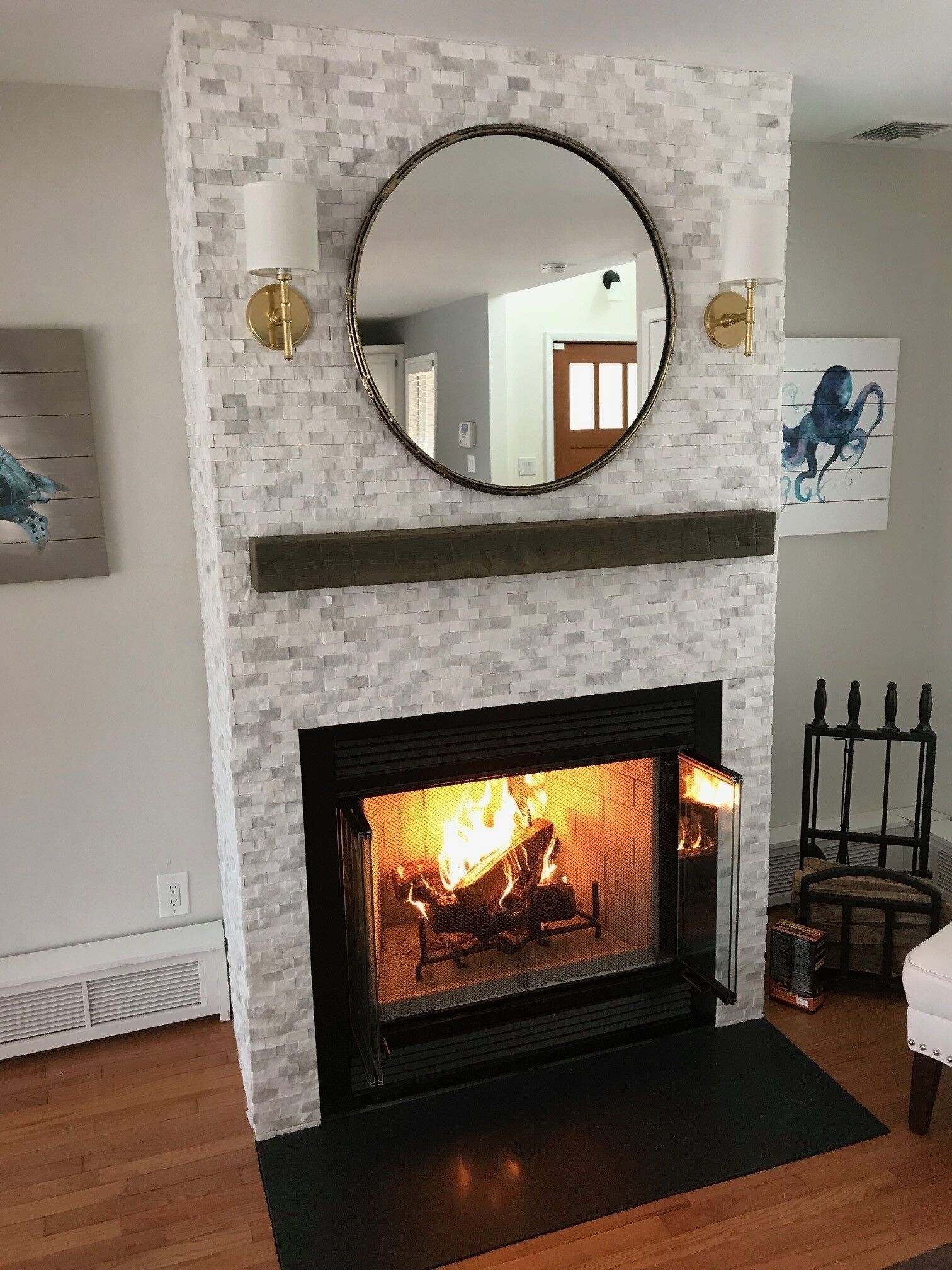 A fireplace with a white brick surround, a round mirror above it, and a wall-mounted light fixture.