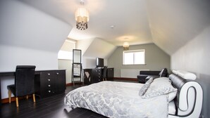 A bedroom with a large bed, a desk, a chair, a dresser, and a mirror. - Manor House (Lisburn)