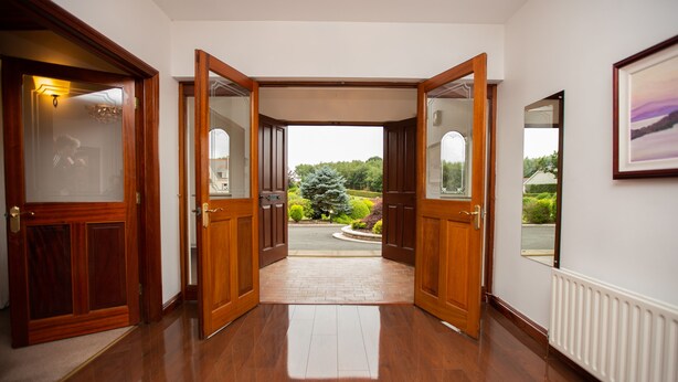 A hallway with wooden doors leading to a garden view. - Manor House (Lisburn)
