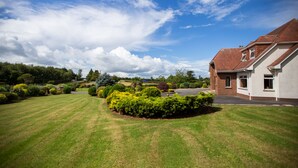 A residential property with a well-maintained lawn, a driveway, and a brick house with a sloped roof. - Manor House (Lisburn)