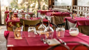 Restaurante com mesas preparadas para refeições, com toalhas de mesa vermelhas e copos de vidro transparente.