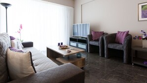 En moderne stue med sofa, lænestol, sofabord og et fladskærms-tv.