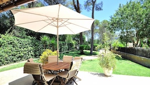 An outdoor patio with a wooden table and chairs, a beige umbrella, and a potted plant. - Villa CA NA CARMEN with garden, private pool in Crestatx and very close to POLLENÇA. Quiet zone. - Free Wifi (Sa Pobla)