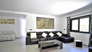 A modern living room with a black leather sofa, a coffee table, and a large abstract painting on the wall. - Villa CA NA CARMEN with garden, private pool in Crestatx and very close to POLLENÇA. Quiet zone. - Free Wifi (Sa Pobla)