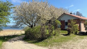 A house with a red roof, a brick exterior, and a front porch. - Quiet 5* vacation home right on the water | WLAN | sauna | fireplace | whirlpool tub (Kosel / Schlei)