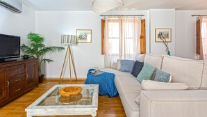 Un salon avec un canapé, une table basse, un téléviseur, une lampe et une plante en pot.