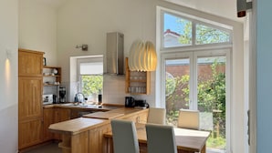 Een moderne keuken met houten kastjes, een centraal eiland en een zithoek met stoelen.