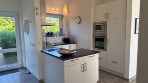 A modern kitchen with white cabinets, a black countertop, and stainless steel appliances. - Holiday house in direct water situation | Sauna | Whirlpool | Fireplace | Free Wi-Fi (Kosel)