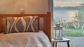 Une chambre à coucher avec un lit, une table de chevet, une lampe et une vue sur un lac.