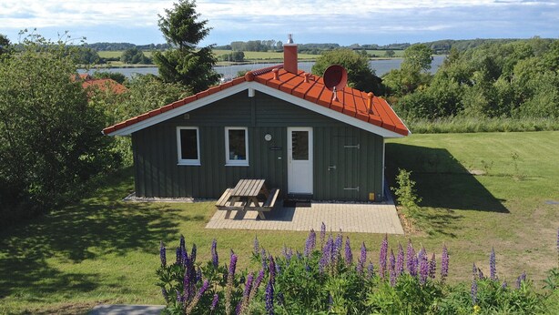 A small, single-story house with a red roof, a front door, and a small porch. - Cozy lodge on a hillside with Schleiblick | Sauna | Fireplace | Free Wi-Fi (Kosel)
