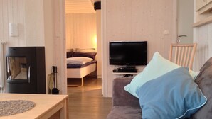 A compact living space with a sofa, a television, a bed, and a dining area. - Cozy lodge on a hillside with Schleiblick | Sauna | Fireplace | Free Wi-Fi (Kosel)