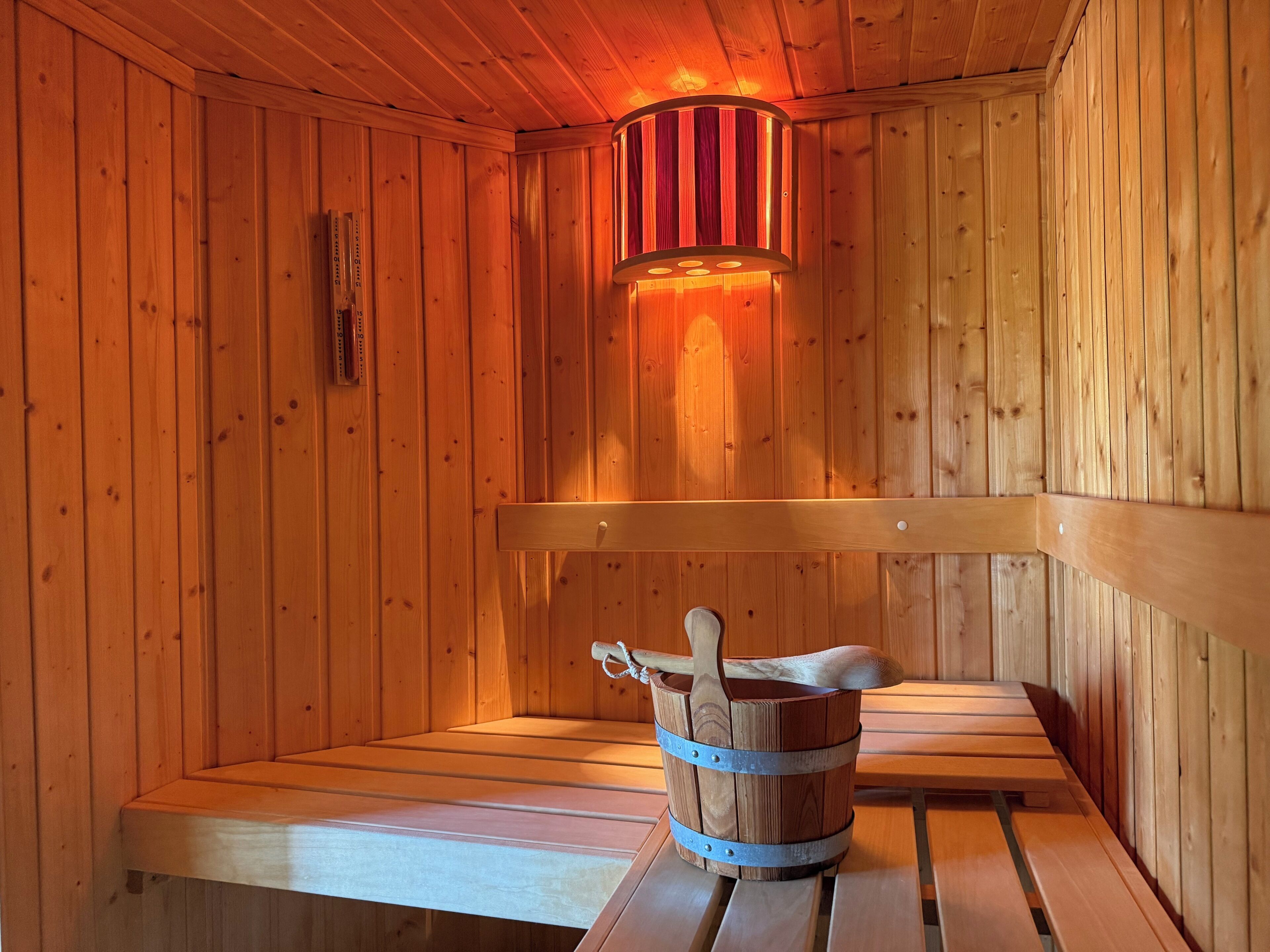 Una sauna de madera con bancos y un balde con una cuchara de madera.