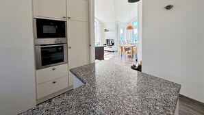 Una cocina moderna con electrodomésticos integrados, encimera de granito y vistas al comedor.