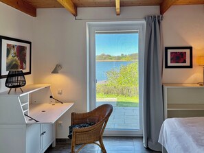 A room with a desk, chair, bed, and a view of a lake through a window. - Schlei Resort Marina Hülsen (Kosel)