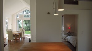 Ein geräumiges Zimmer mit einem Holzespeisetisch, einem Bett und einem kleinen Tisch mit einer roten Lampe.