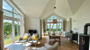 Ein geräumiger Wohnbereich mit großem Esstisch, bequemen Sitzgelegenheiten, einem Fernseher und einem Kamin.