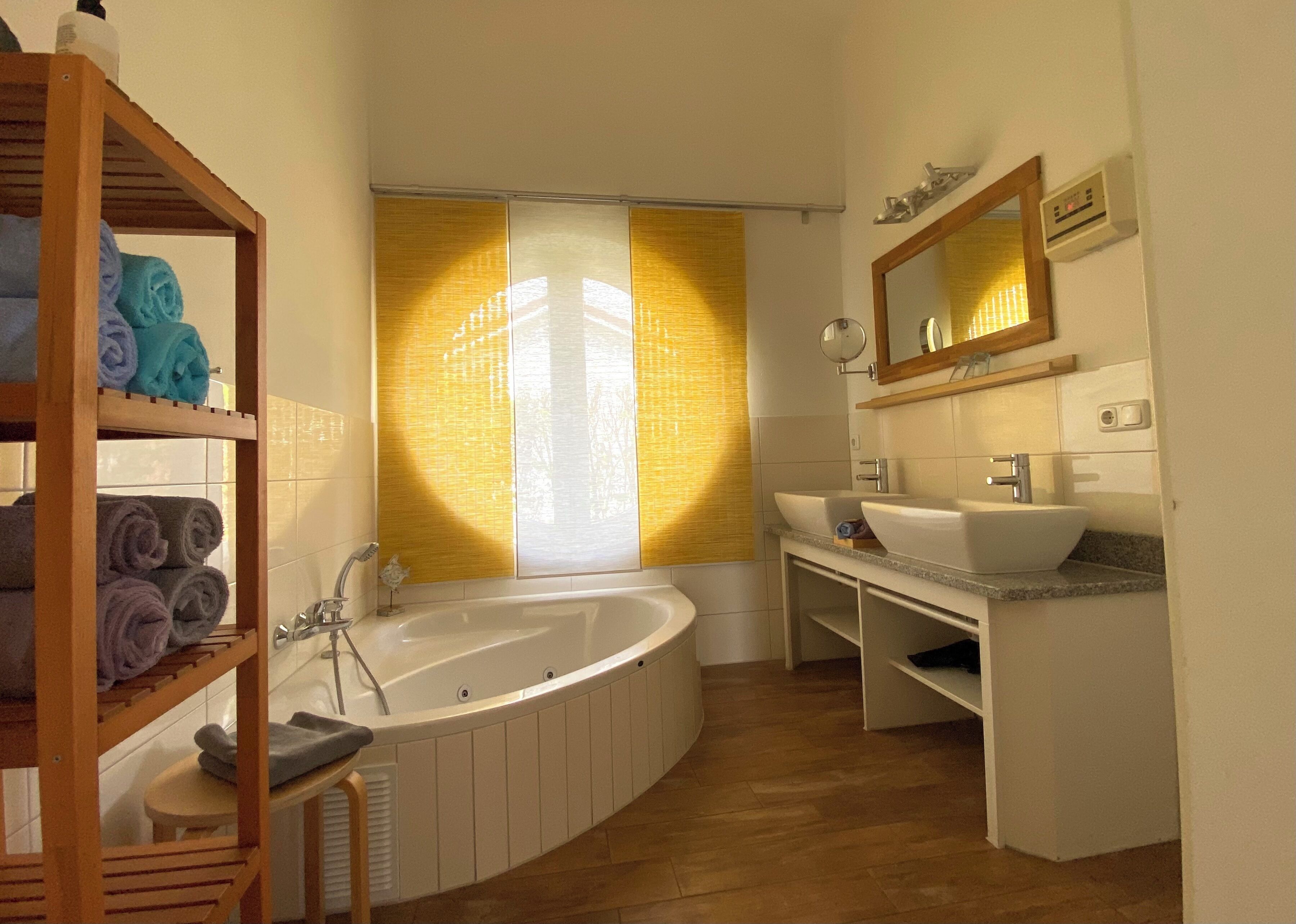 A modern bathroom with a freestanding bathtub, a vanity with a sink, and a shelf with towels.