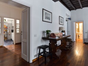 A spacious room with hardwood flooring, a wooden table, two framed pictures on the wall, and a door leading to another room. - Spanish Steps Apartment (Rome)