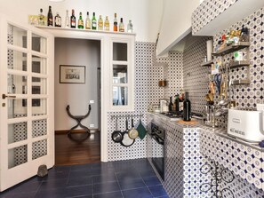 A kitchen with patterned tiles, a white cabinet with bottles, and a hanging pot rack. - Spanish Steps Apartment (Rome)
