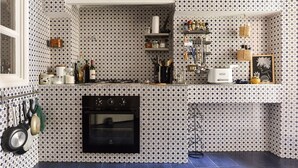 Una cocina con salpicadero decorativo, estufa, horno y diversos utensilios.