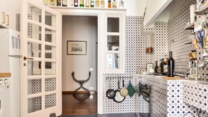 Una cocina con un armario blanco, un colgador para ollas y salero y un respuesto de azulejos.