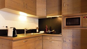 Une cuisine moderne avec des meubles en bois, un four à micro-ondes encastré, une machine à café et un évier.
