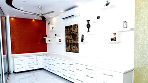 A modern hotel room with a white cabinet, marble flooring, and a red accent wall. - Hotel Blessings (New Delhi)