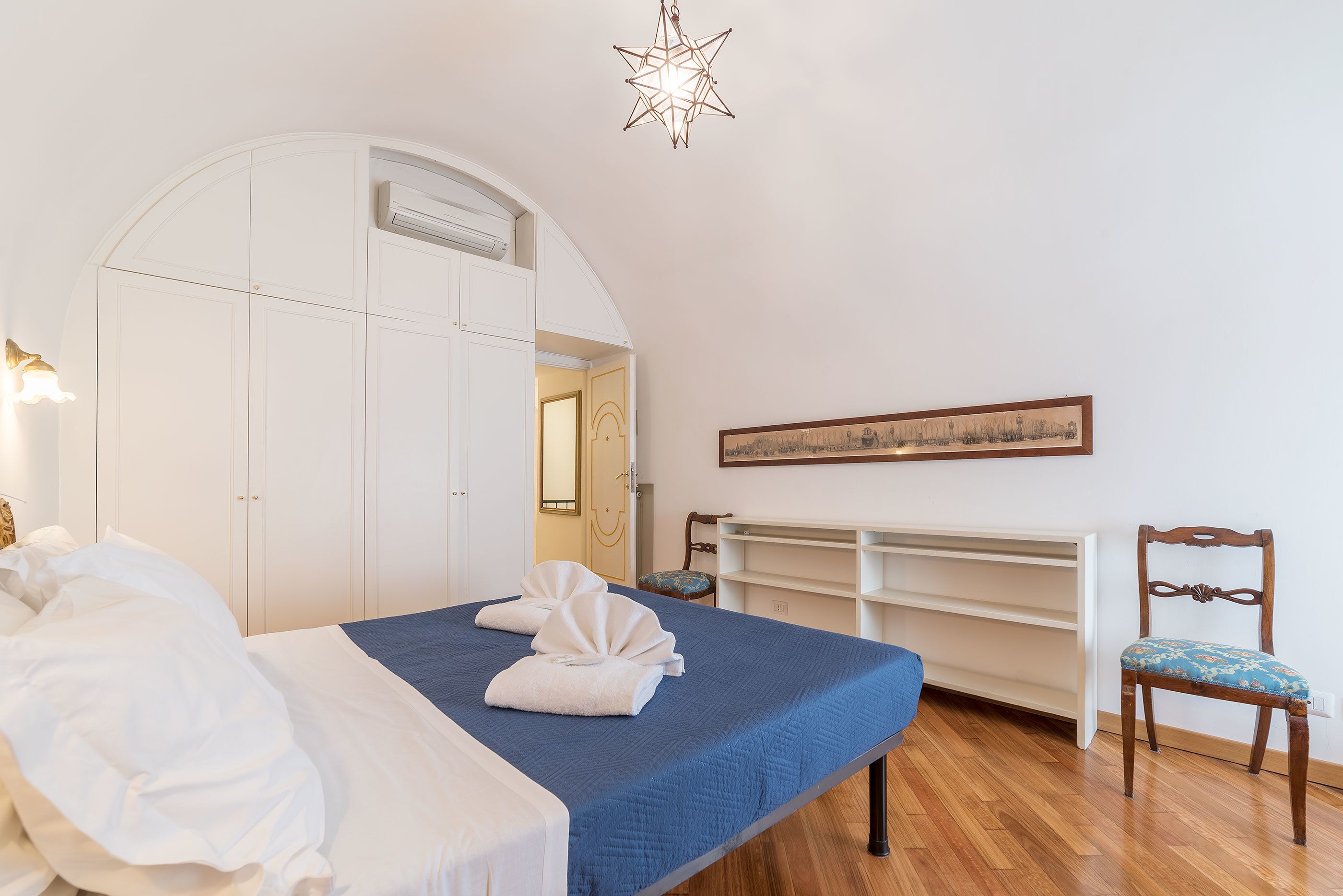 Une chambre à coucher avec un lit, une chaise, une armoire et un tableau au mur.