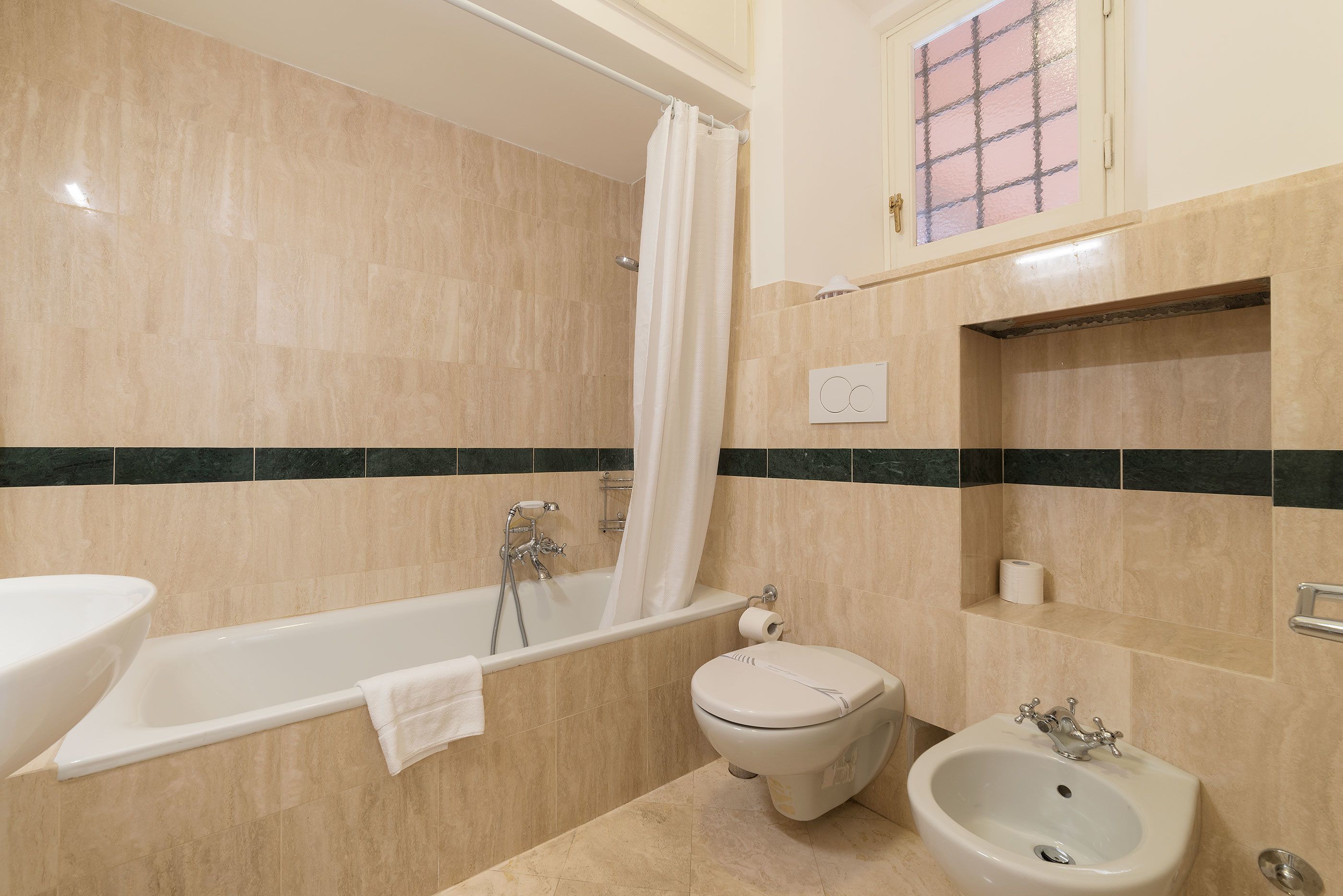 A bathroom with a bathtub, toilet, bidet, and sink.