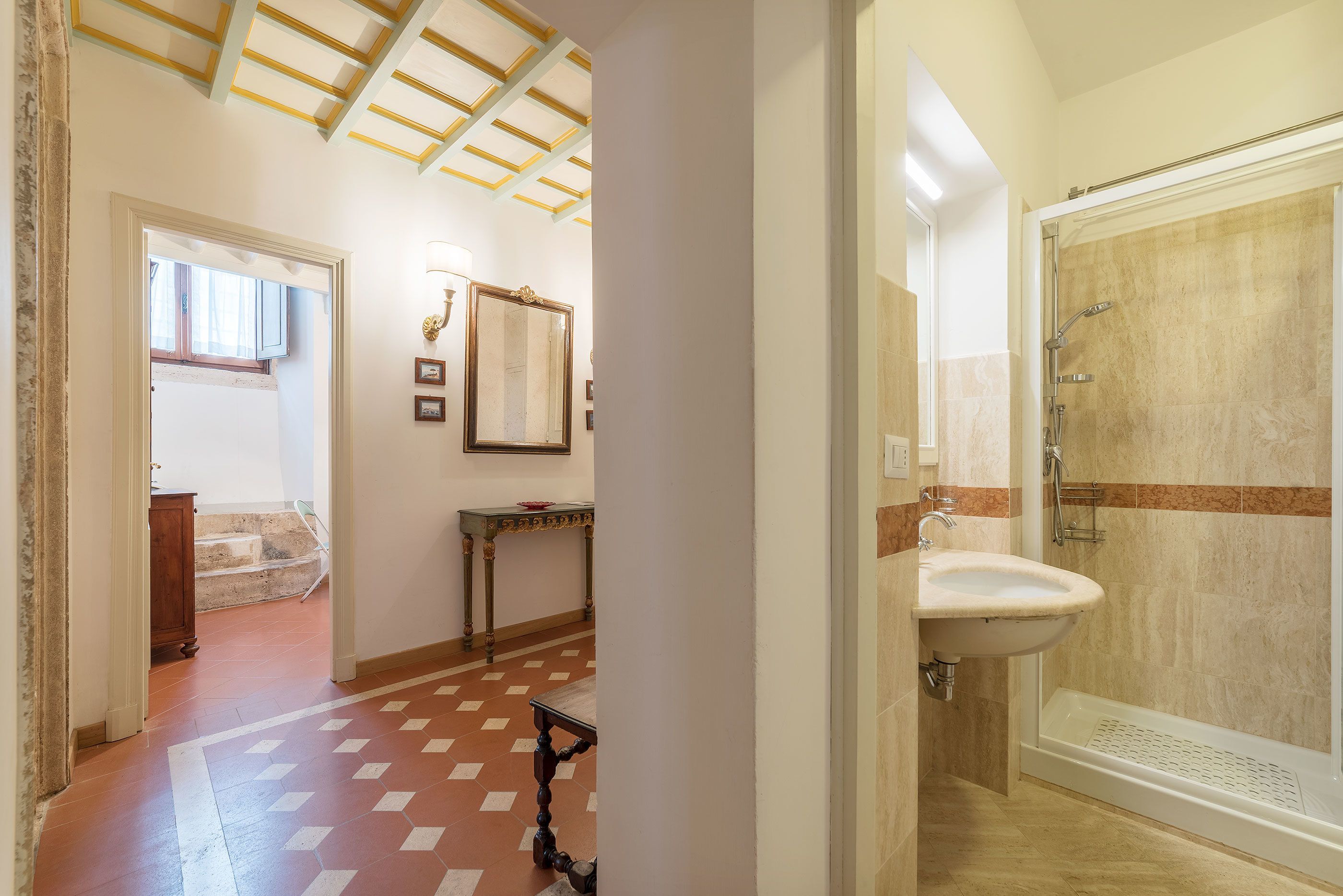 A bathroom with a shower, sink, and tiled floor.