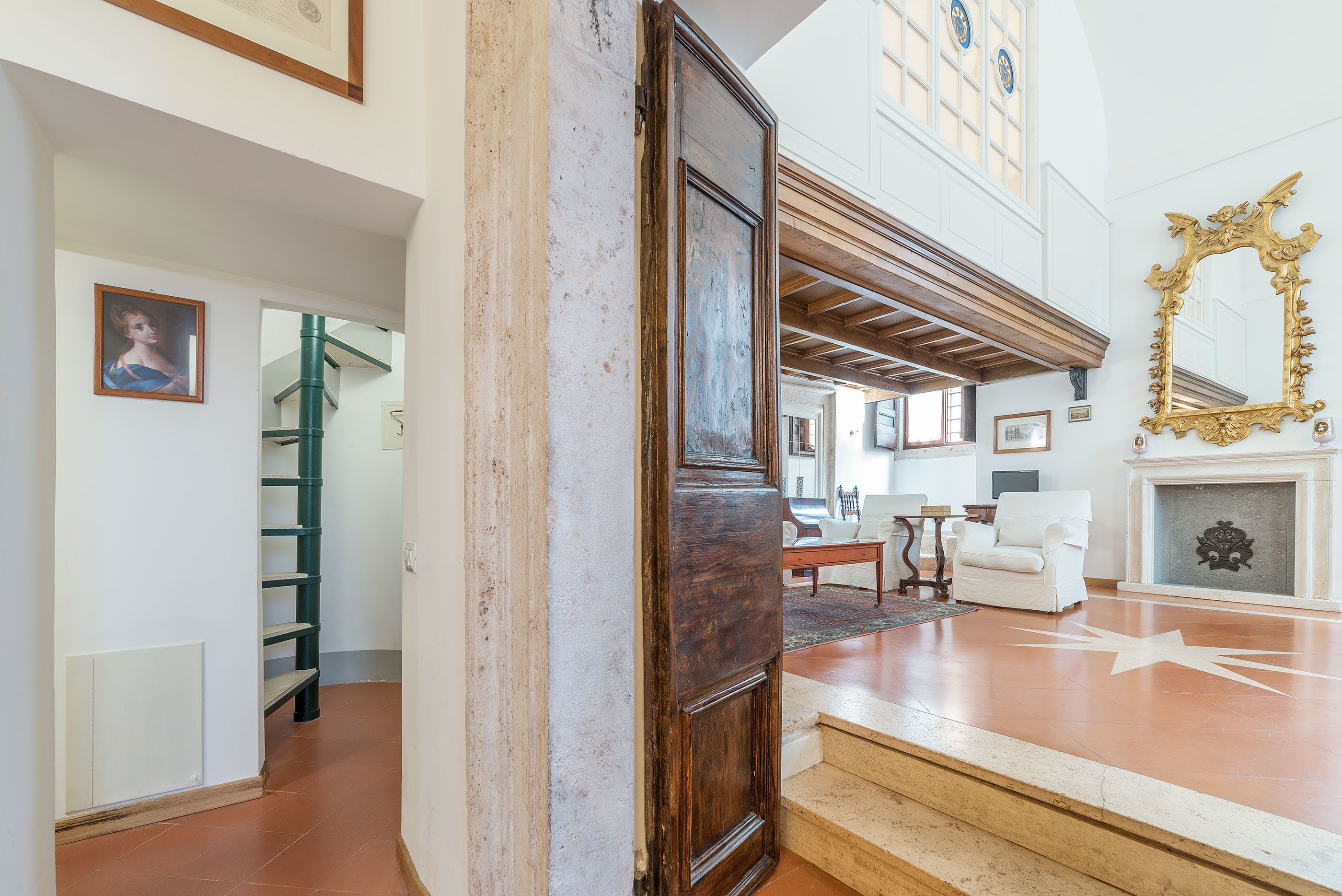 A spacious room with a staircase, a fireplace, and a large mirror.