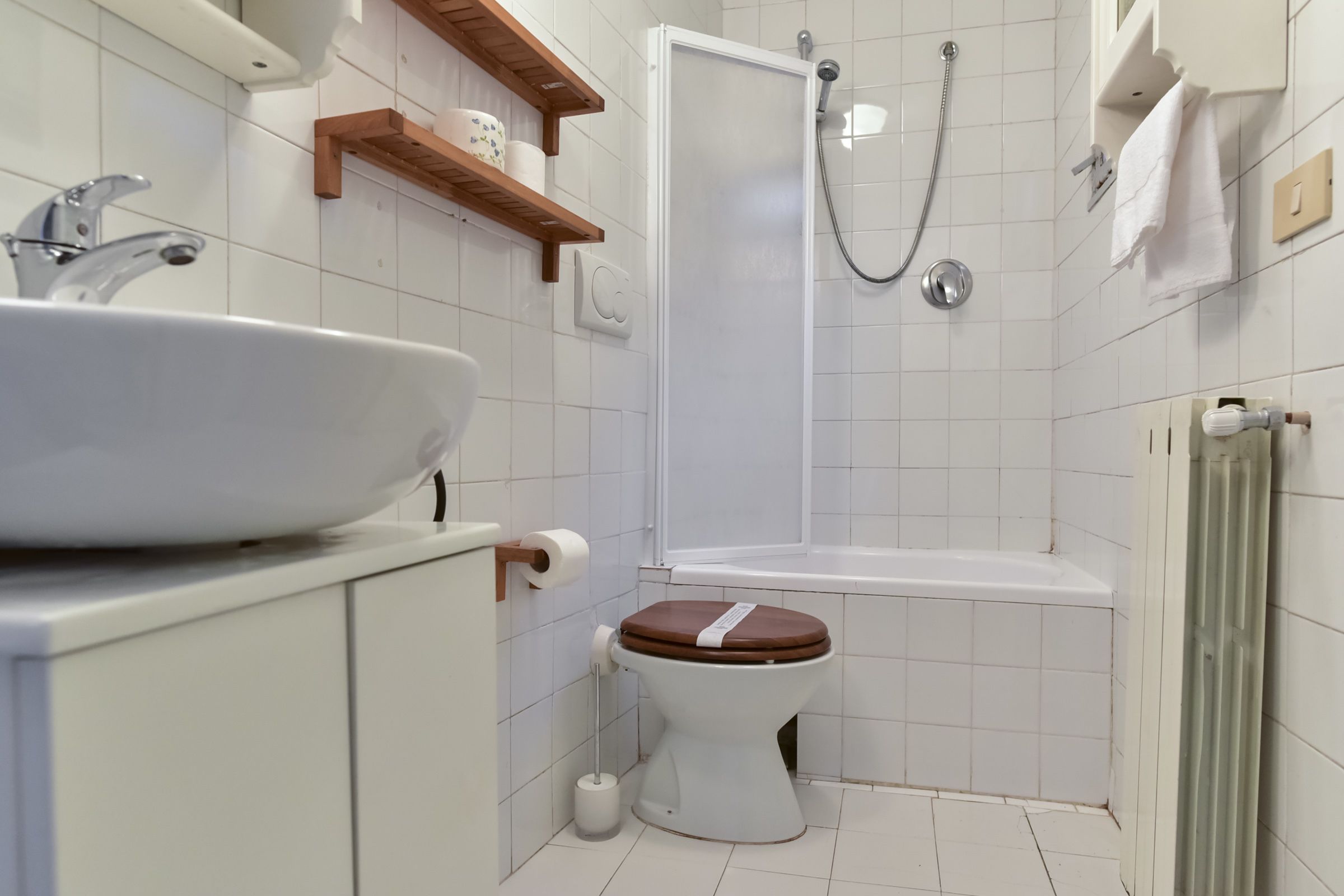 Een moderne badkamer met een wit wastafel, toilet en douche.