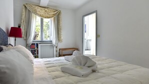 Ein Schlafzimmer mit einem Bett, einer roten Lampe, einem Fenster mit Vorhängen und einem Bücherregal.