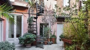 Ein Innenhof mit Blumentöpfen, einer Metall-Wendeltreppe und einer Tür.