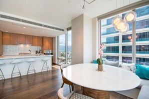 A modern kitchen with a central island, bar stools, and a dining area with a round table and chairs. - Luxurious Two bedroom Unit with Panoramic Ocean View in ONE Ala Moana (Honolulu)